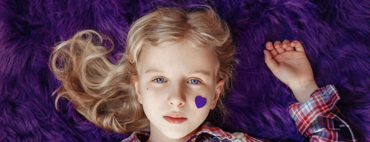 girl laying on purple rug with heart on cheek