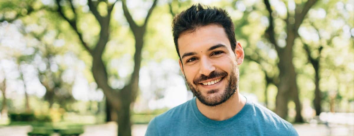 smiling man with yoga mat outdoors